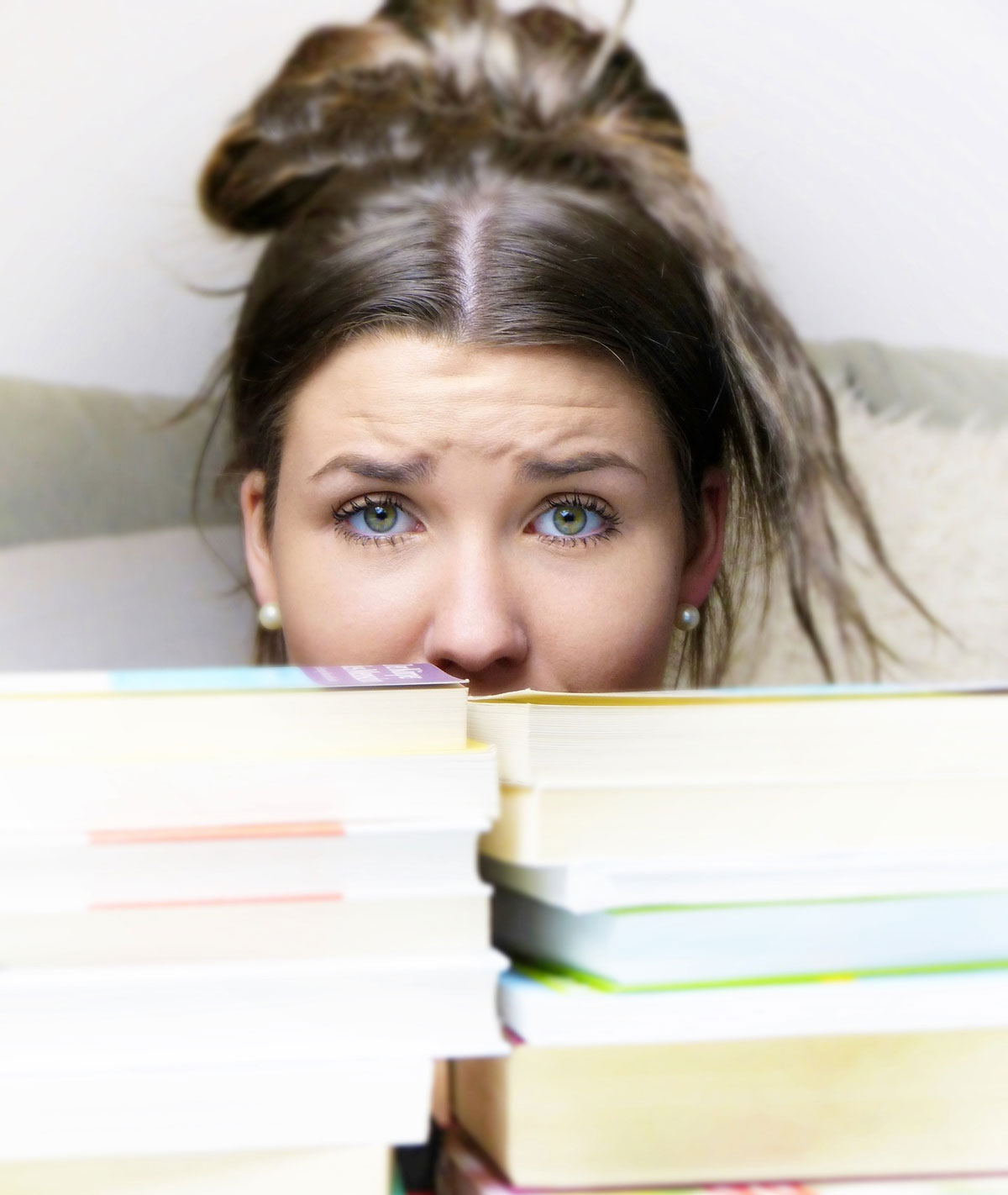 Teenage Girl Peeking Over Stack of Books
